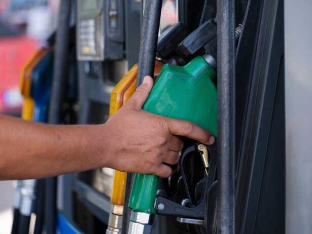 The hand of a fleet driver returns the gas pump to the filling station after filling his truck with fuel.