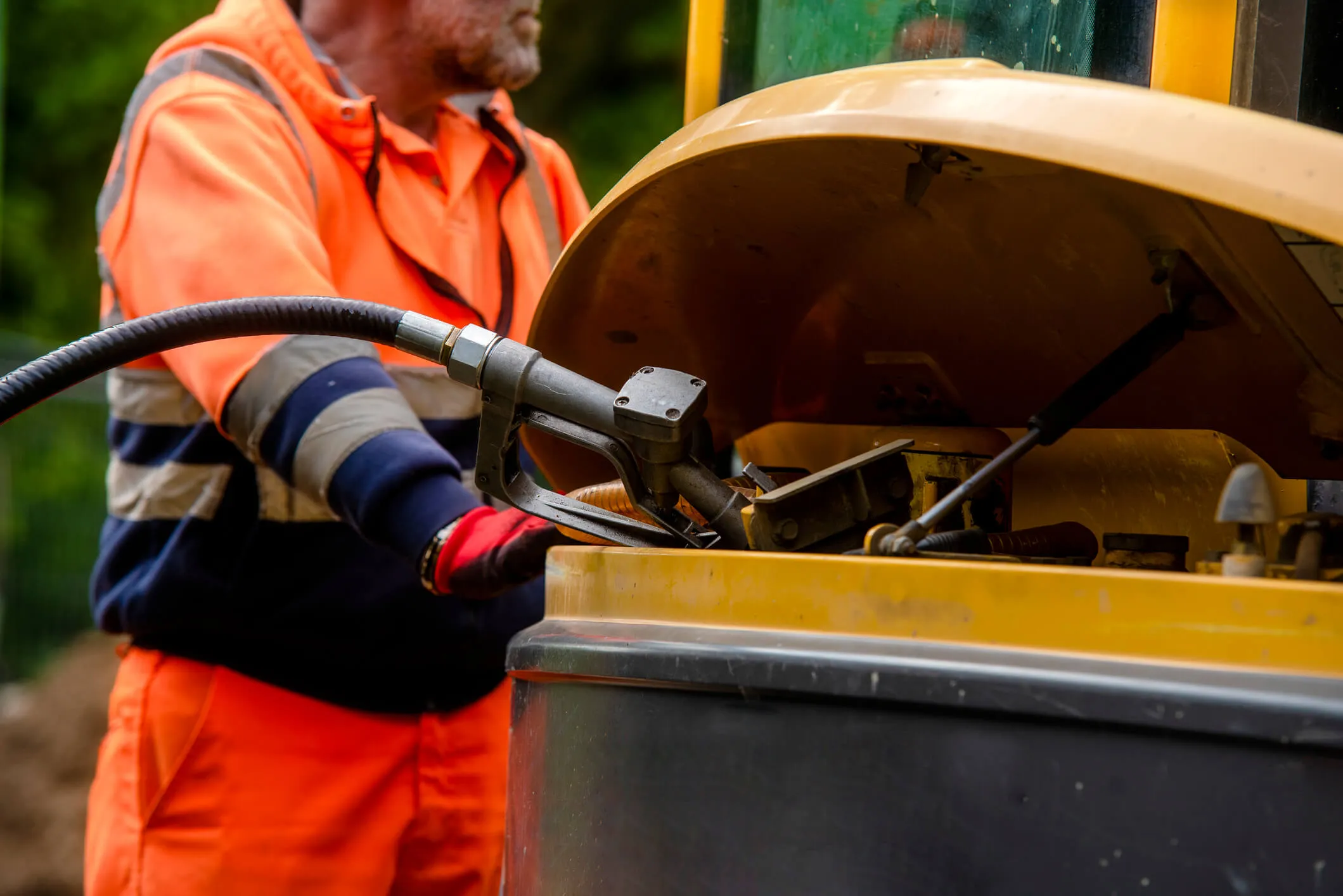 A worker at a construction site fuels his construction vehicle.