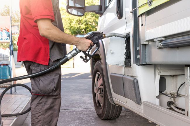 A plumber fuels his fleet van at a gas station with a fuel card.