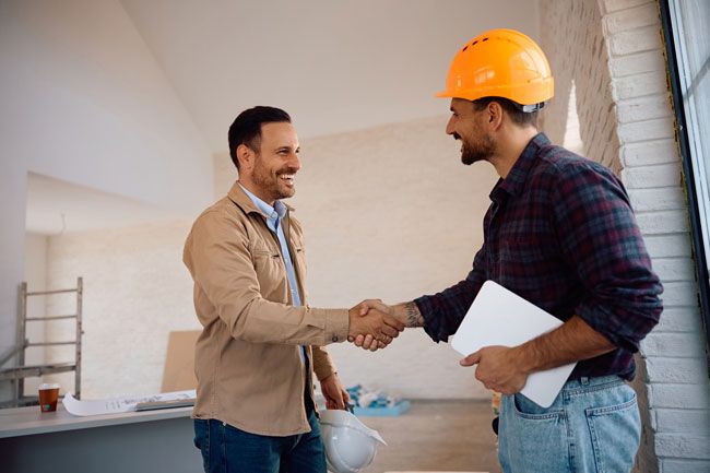 A contractor and business owner confer at a construction site.