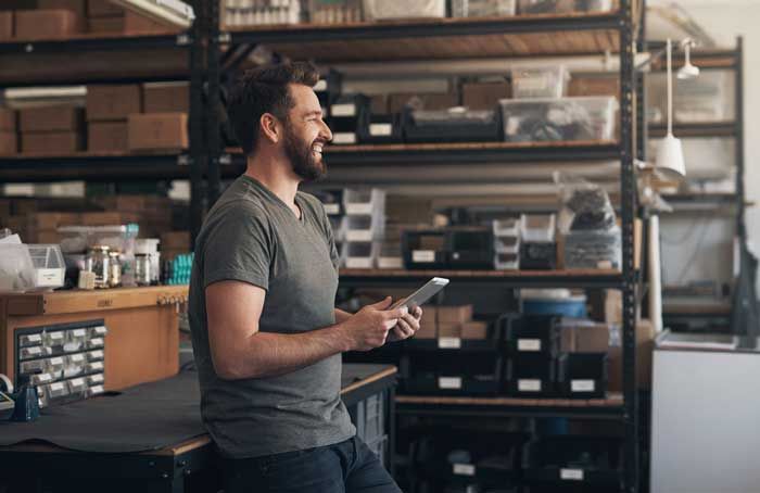 A happy business owner reviews fleet fuel card data on his tablet in his shop