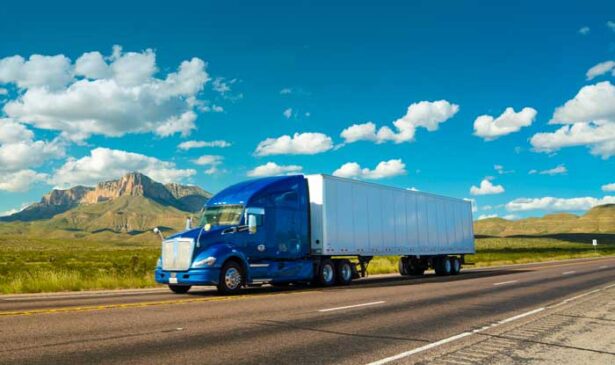 A semi truck with a blue cab travels its fleet route.